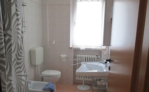Een badkamer met toilet, bidet en wastafel.