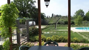 Een terras met een tafel en stoelen, een zwembad en een verzorgd gazon.
