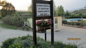 A sign for an agricultural business selling direct to consumers, with a flower pot and a pool in the background.