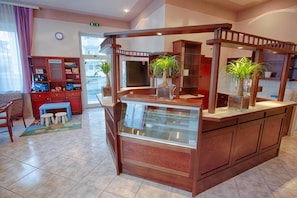 A hotel lobby with a wooden counter, a children's play area, and a large window.
