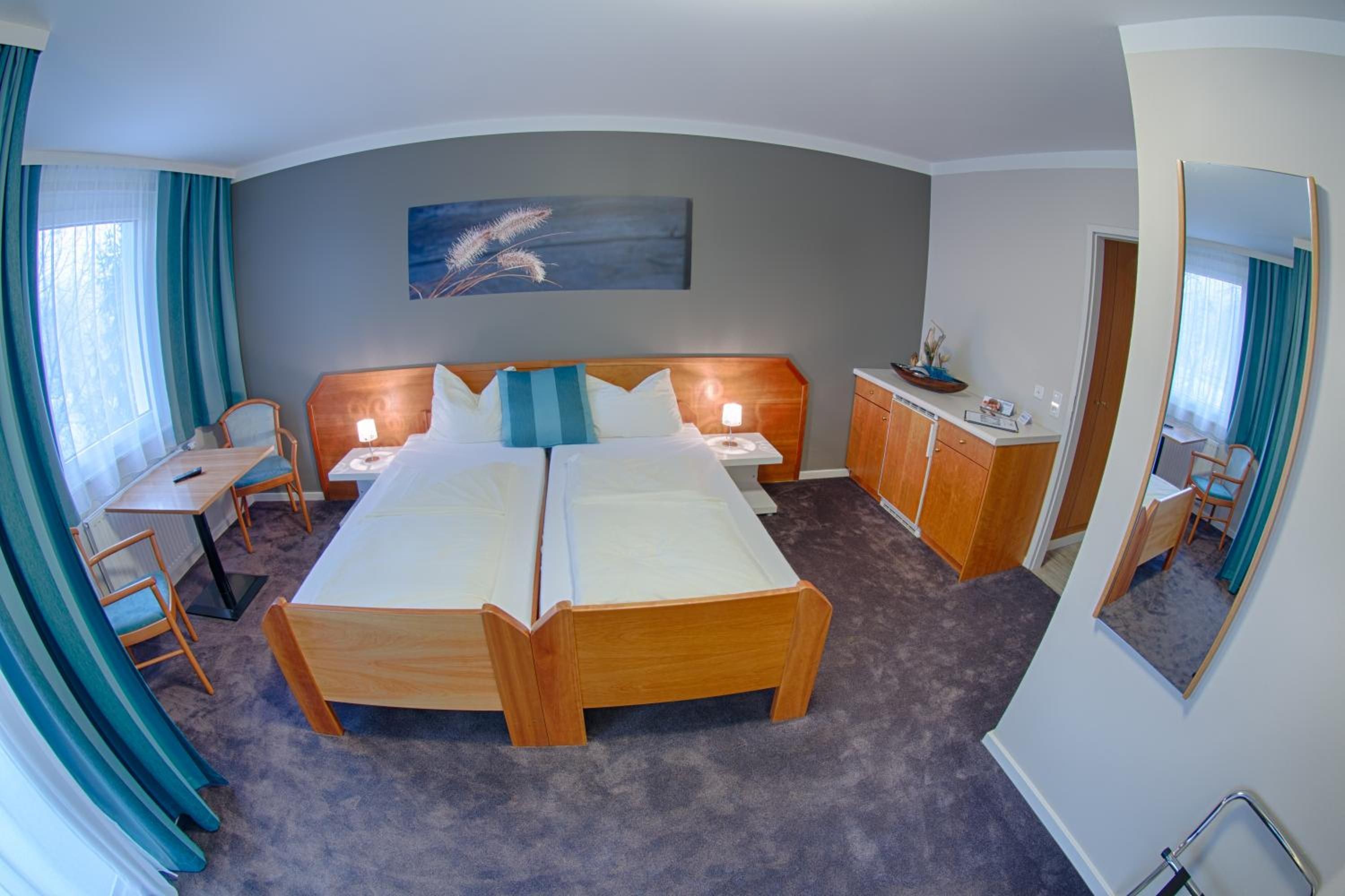 Ein Hotelzimmer mit Doppelbett, Schreibtisch, Stuhl, Schrank und einem Gemälde an der Wand.