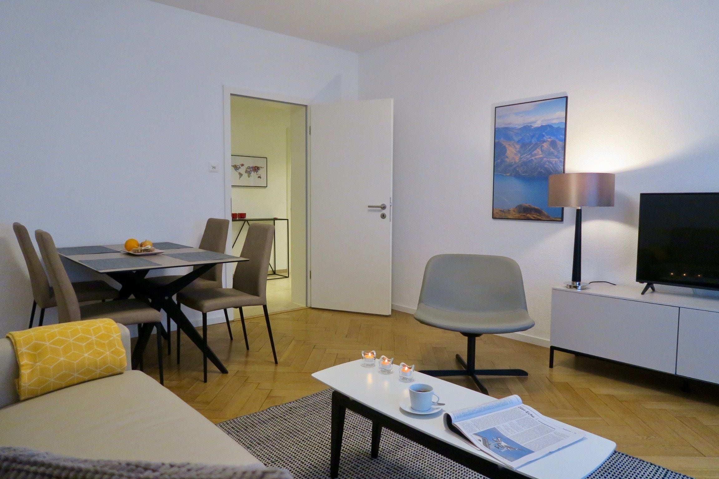 Une chambre d’hôtel moderne dotée d’un coin repas, d’une télévision et d’un tableau au mur.