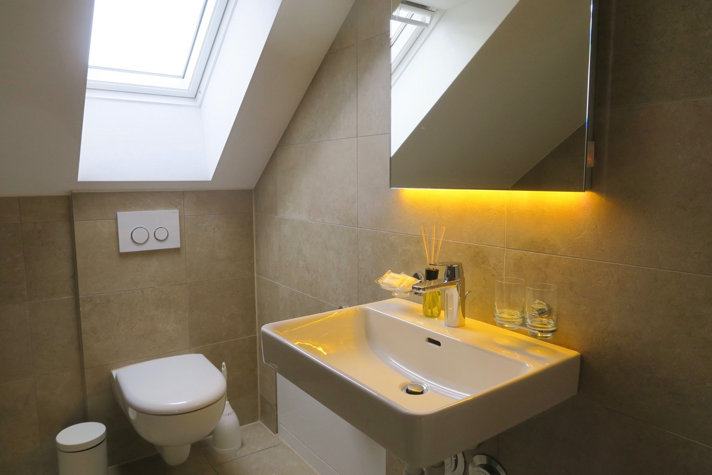Une salle de bain moderne avec un puits de lumière, un lavabo blanc et des toilettes.