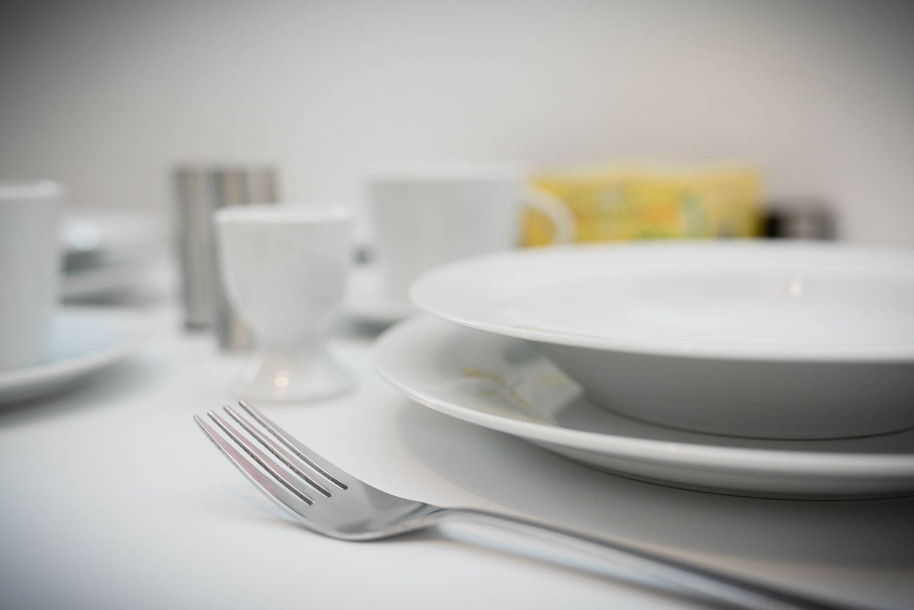 Una colazione con un piatto bianco, una forchetta, una tazza e una scatola di cereali.