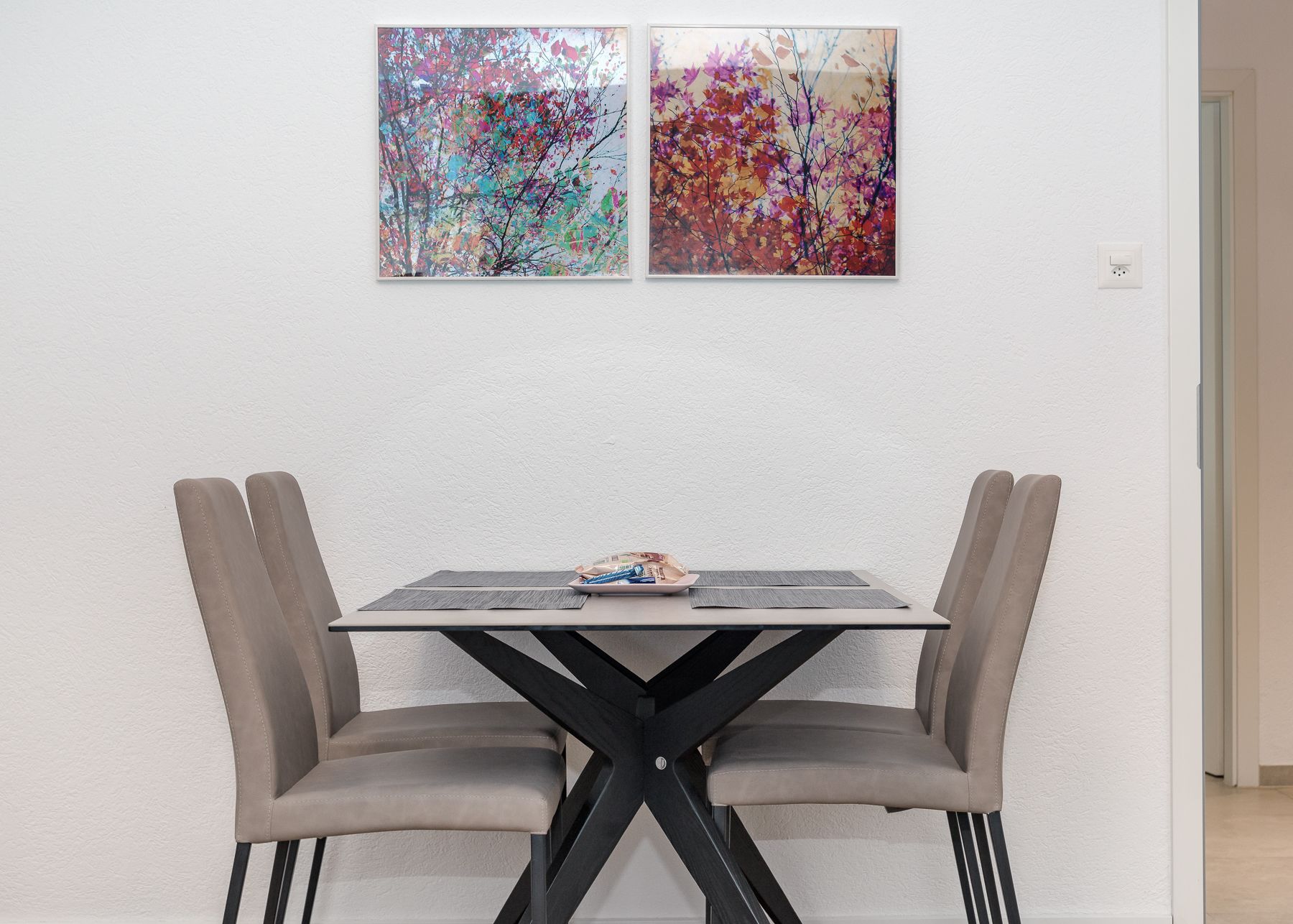 Una mesa de comedor con dos sillas, una lámpara de mesa pequeña y un cuadro en la pared.