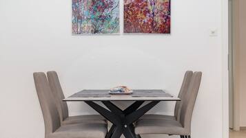 A dining table with two chairs, a small table lamp, and a framed picture on the wall.