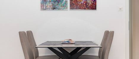 Una mesa de comedor con dos sillas, una lámpara de mesa pequeña y un cuadro en la pared.
