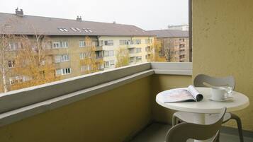 Ein Balkon mit Tisch und Stühlen, der auf eine Reihe von Wohngebäuden blickt.