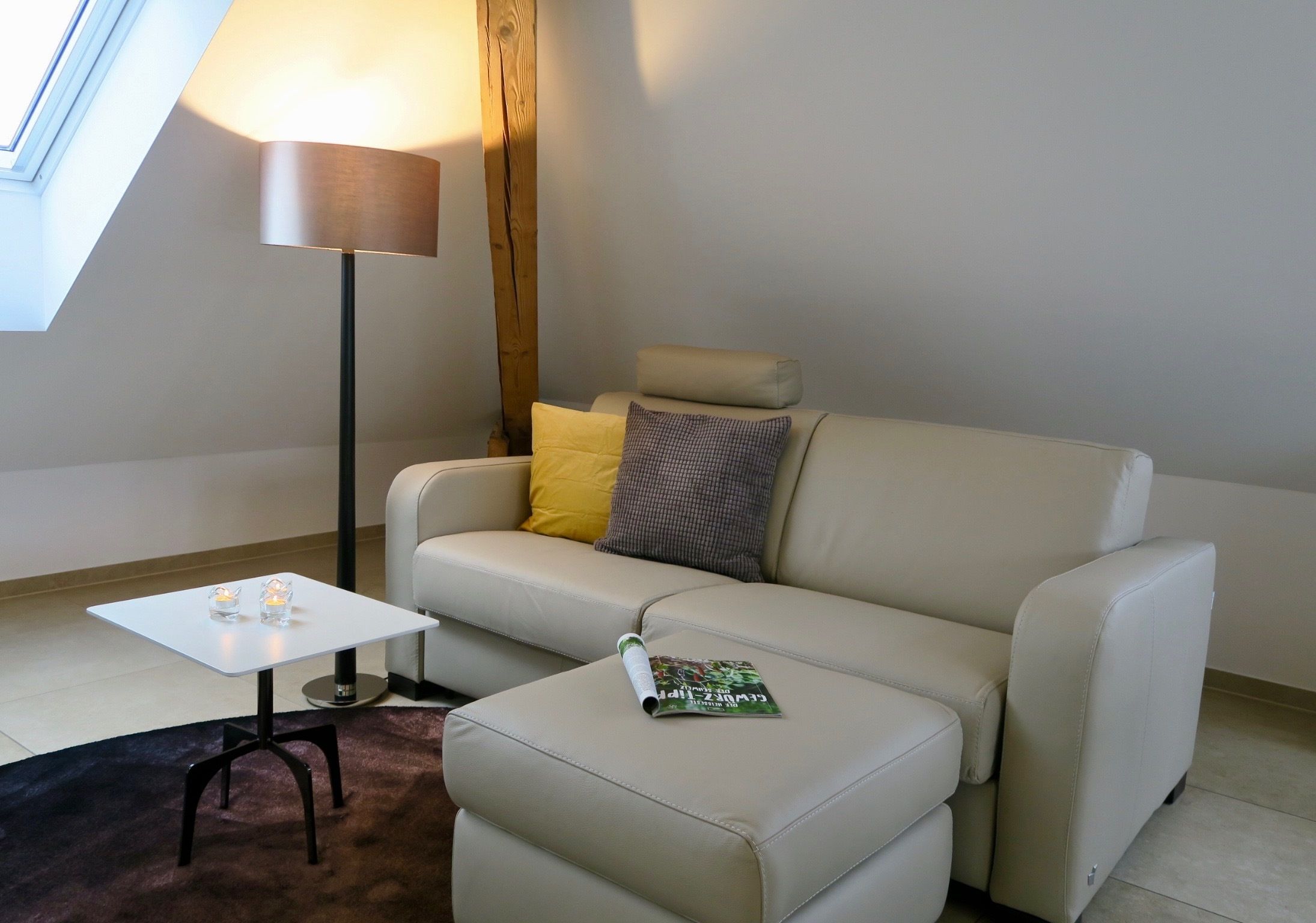 A modern living room with a sofa, a small table, and a floor lamp.