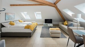 A modern loft bedroom with a bed, sofa, TV, and a dining area. - Zurich Furnished Homes (Zürich)