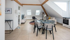A modern loft-style room with a dining area, a sofa, and a kitchen. - Zurich Furnished Homes (Zürich)