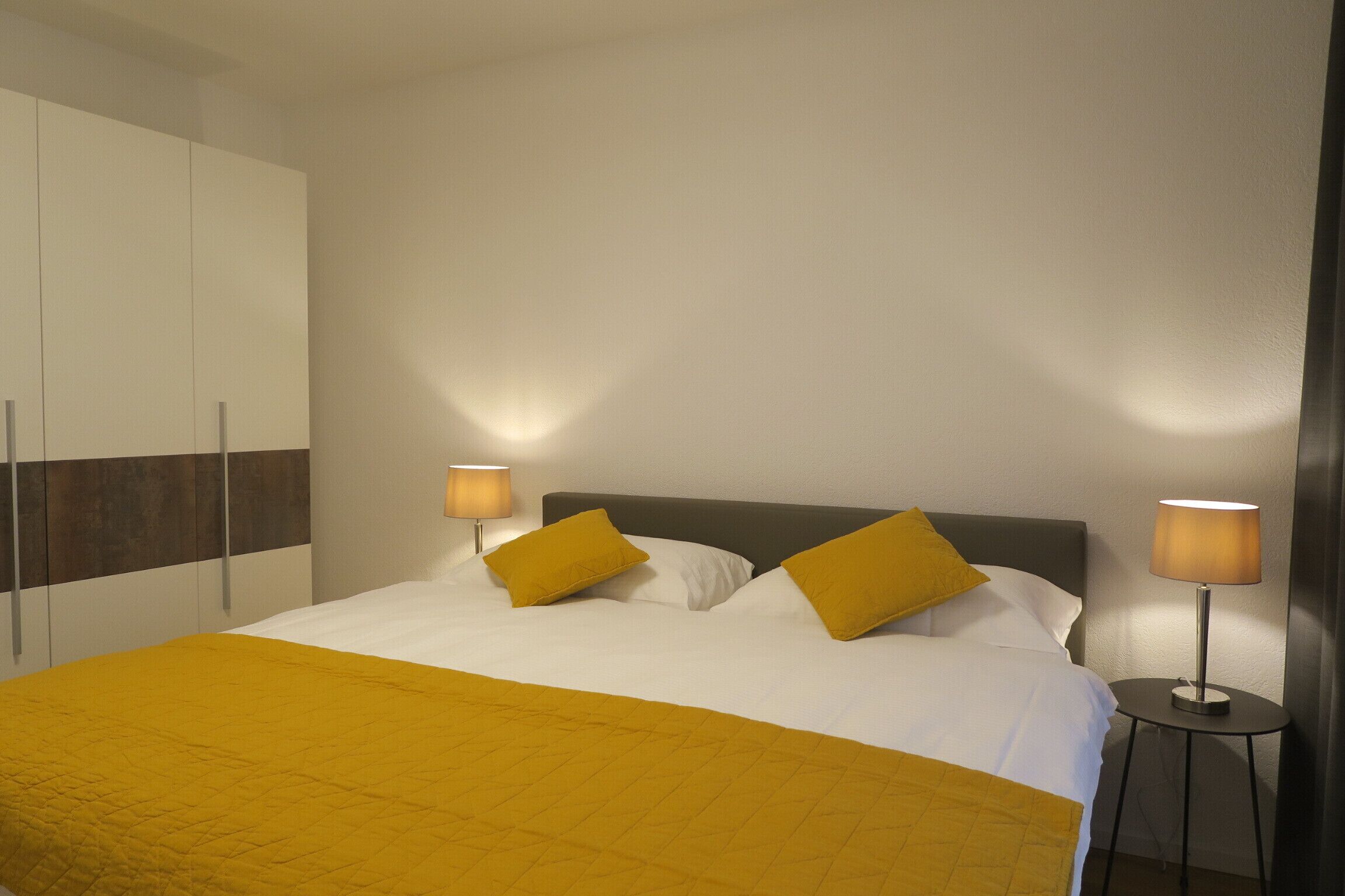 Een hotelkamer met een bed, twee bedlampen, een kledingkast en een nachtkastje.