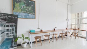 A modern bar area with a wooden counter and stools, a large map on the wall, and a poster with a family home image. - Lantai Dua Jogja - Hostel (Depok)