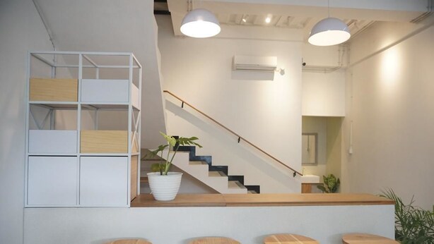 A modern interior with a staircase, a white shelving unit, and wooden stools. - Lantai Dua Jogja - Hostel (Depok)