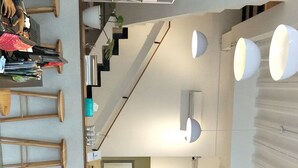 A spacious living area with a staircase, a dining area, and a kitchen. - Lantai Dua Jogja - Hostel (Depok)
