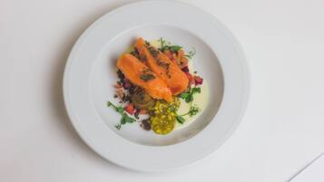 A white plate with salmon, mushrooms, and greens.
