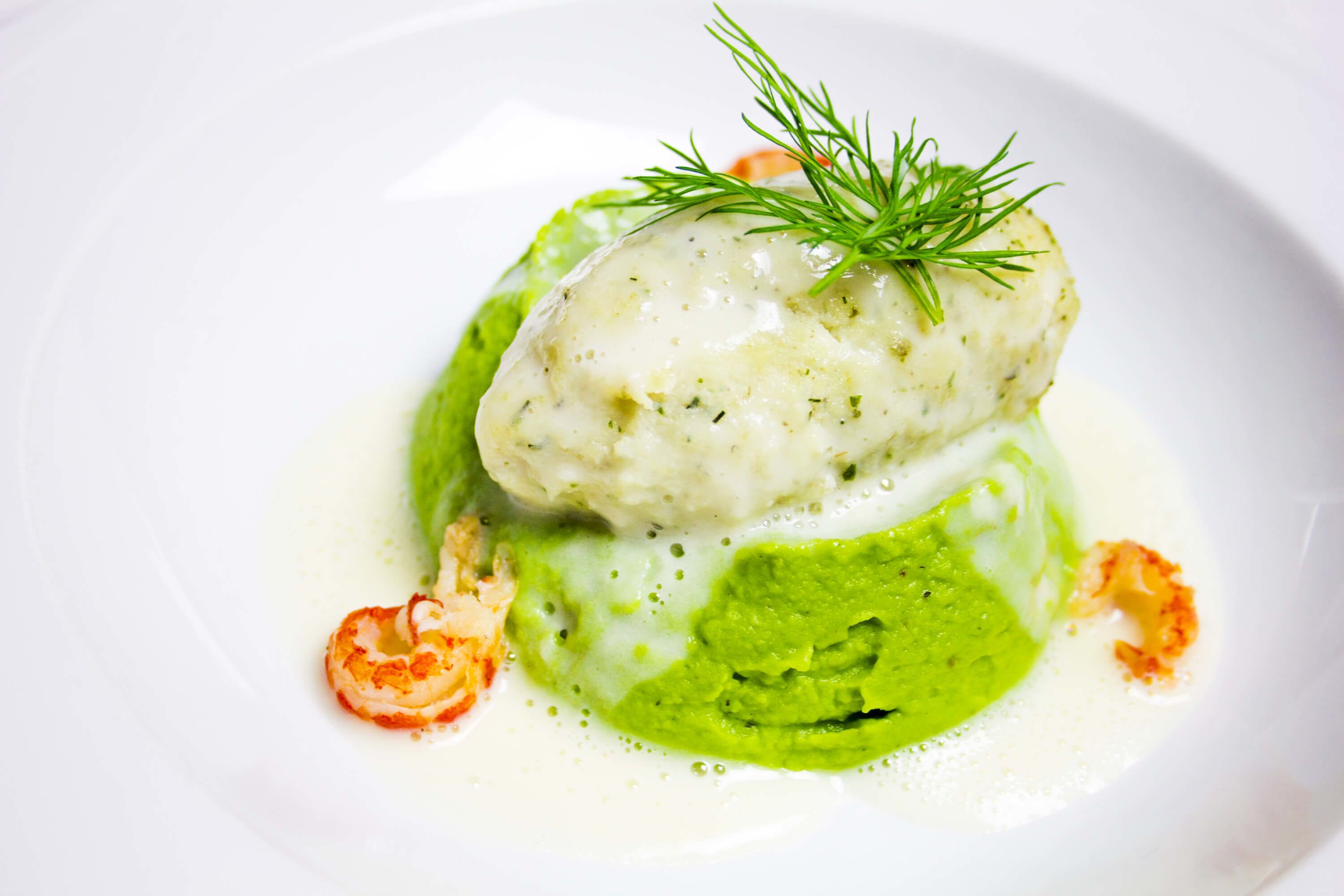 Prato com molho cremoso, purê verde e guarnição de endro.