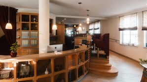 A spacious living area with a wooden bar, shelves with bottles, a laptop, and a red armchair.