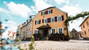 A traditional European building with a cobblestone courtyard, a staircase leading to the entrance, and a sign indicating it is a restaurant.