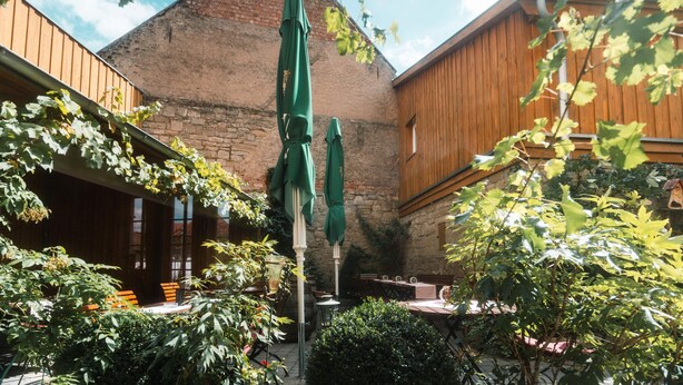 A courtyard with wooden benches, a table, and a stone wall.