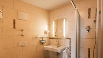 A modern bathroom with a sink, mirror, and shower.