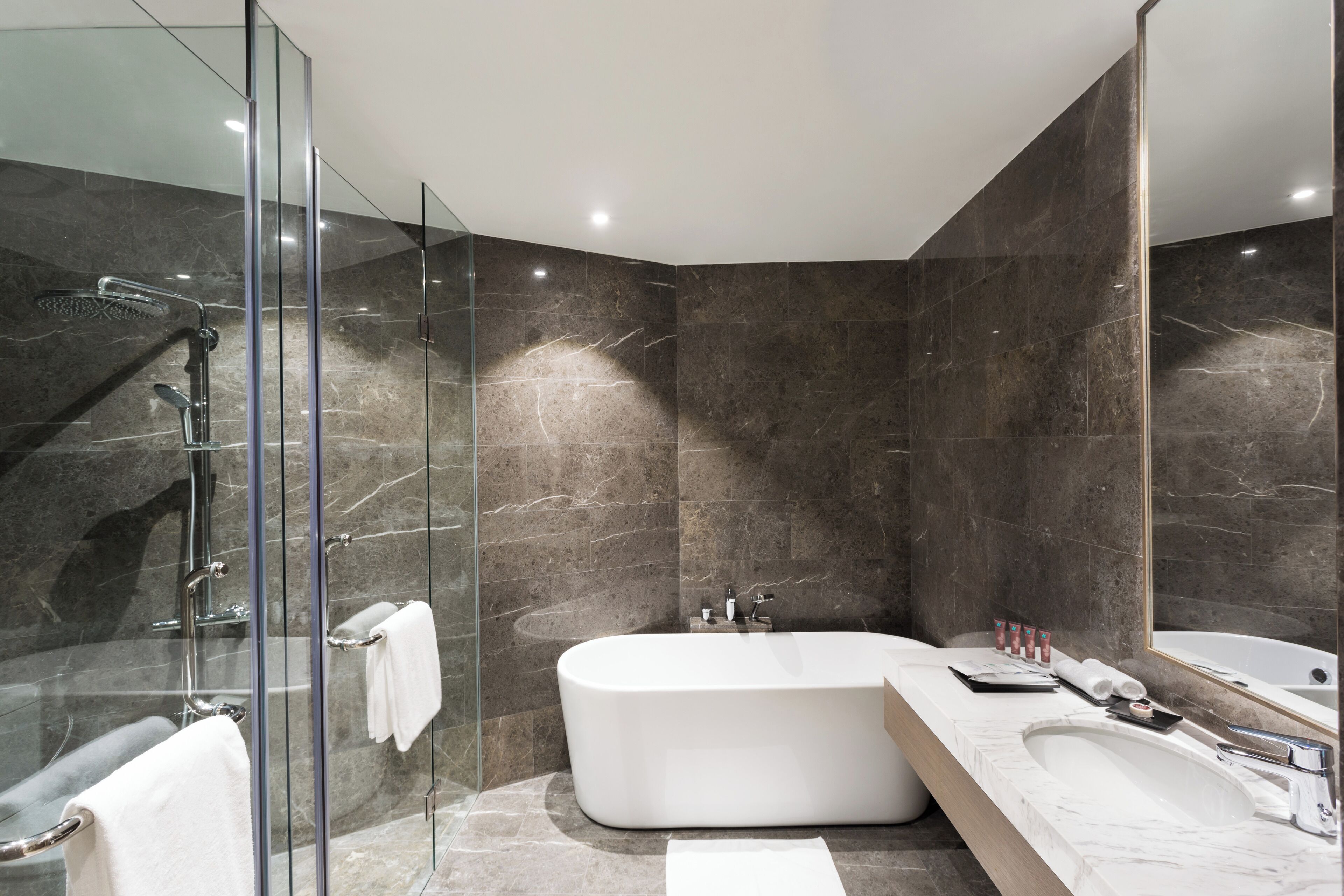 A modern bathroom with a glass-enclosed shower, a freestanding bathtub, and a large mirror.