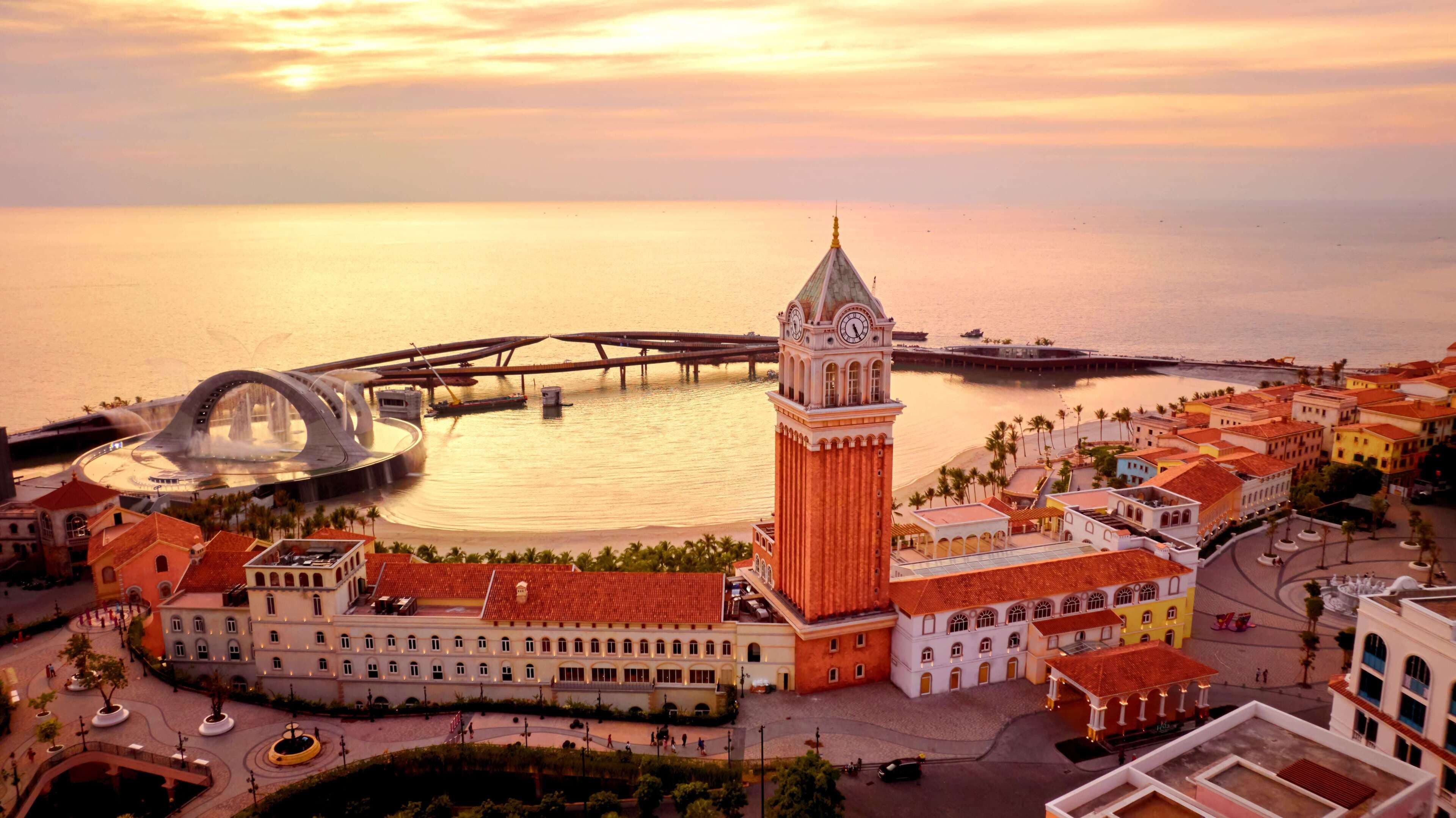 A coastal town with a prominent clock tower, a bridge, and a waterfront promenade.