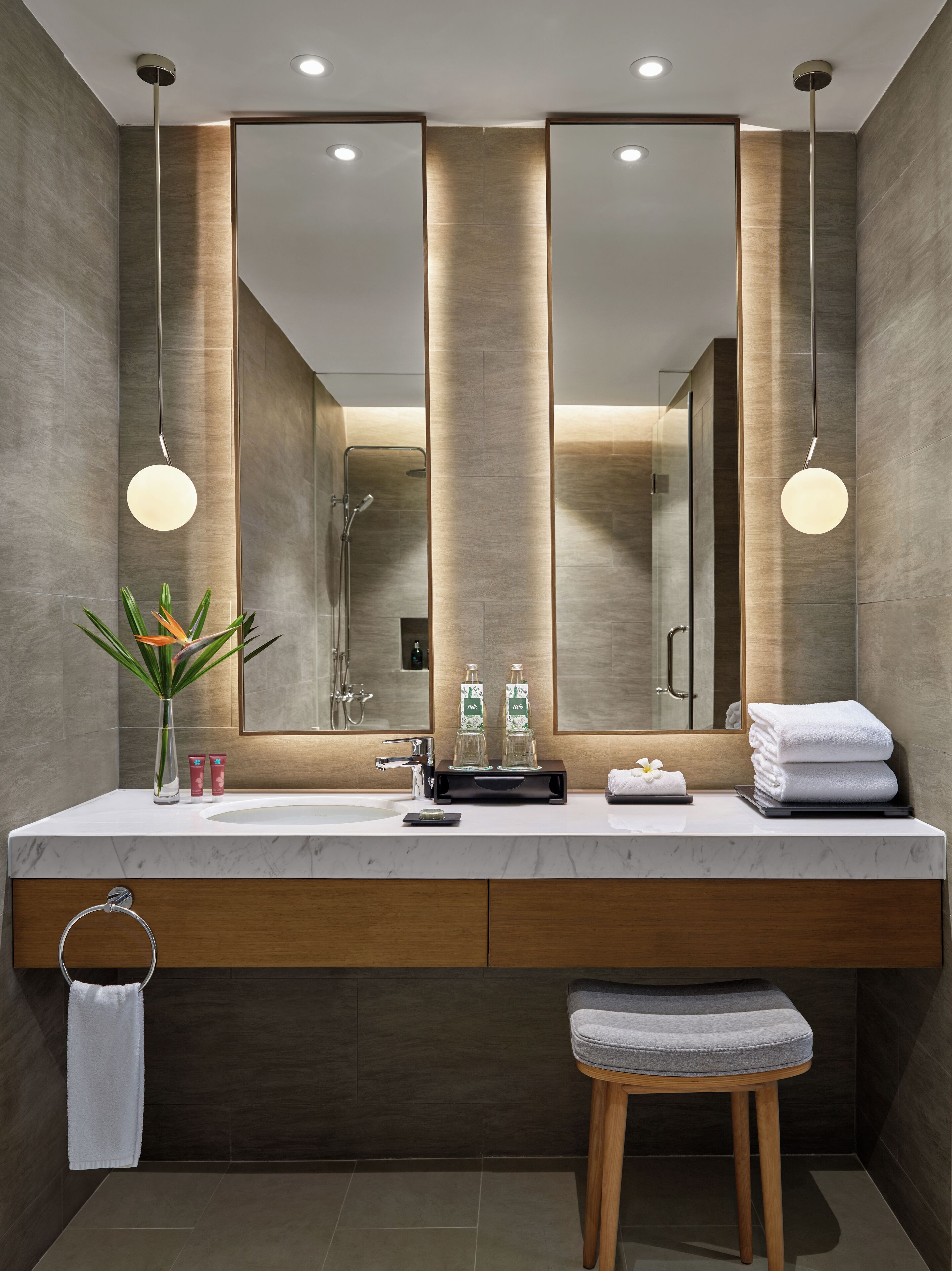 Un bagno moderno con un grande specchio, due lampade a sospensione, un mobile lavabo e un portasciugamani.