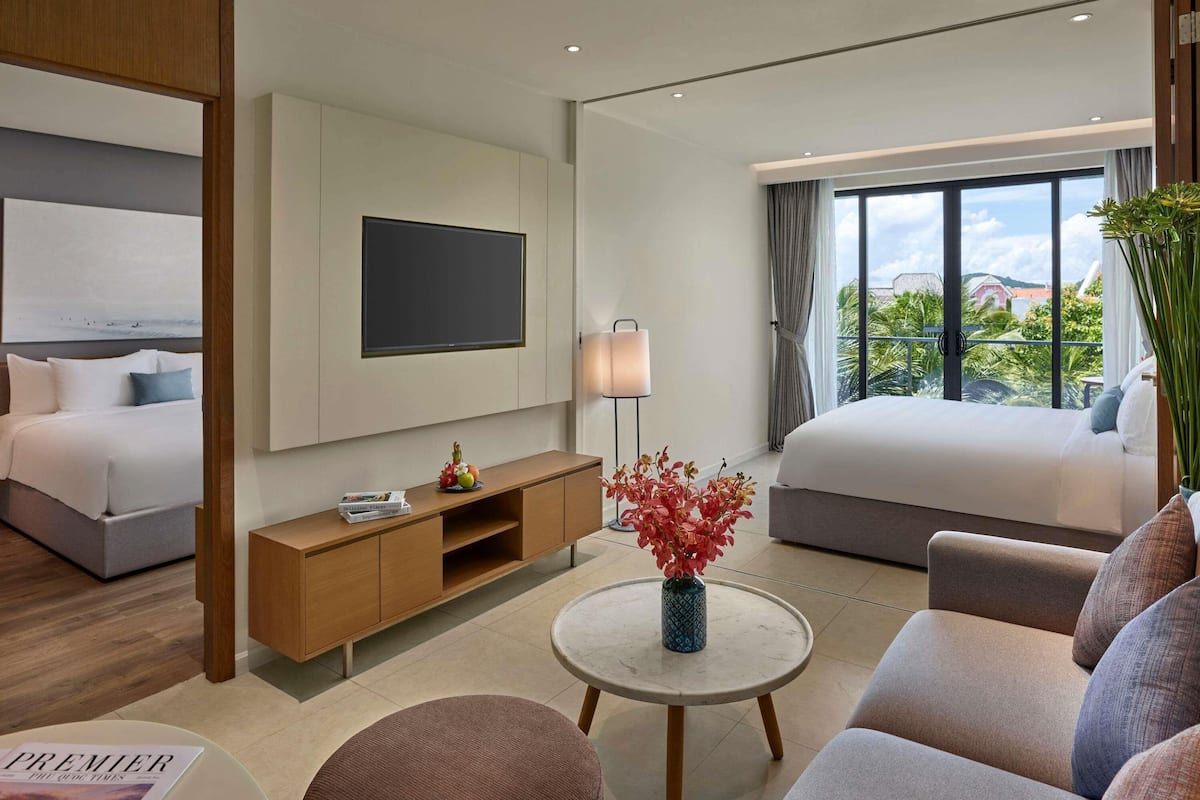 Un hotel moderno con cama, televisión, mesita de noche, sofá y vistas al exterior.