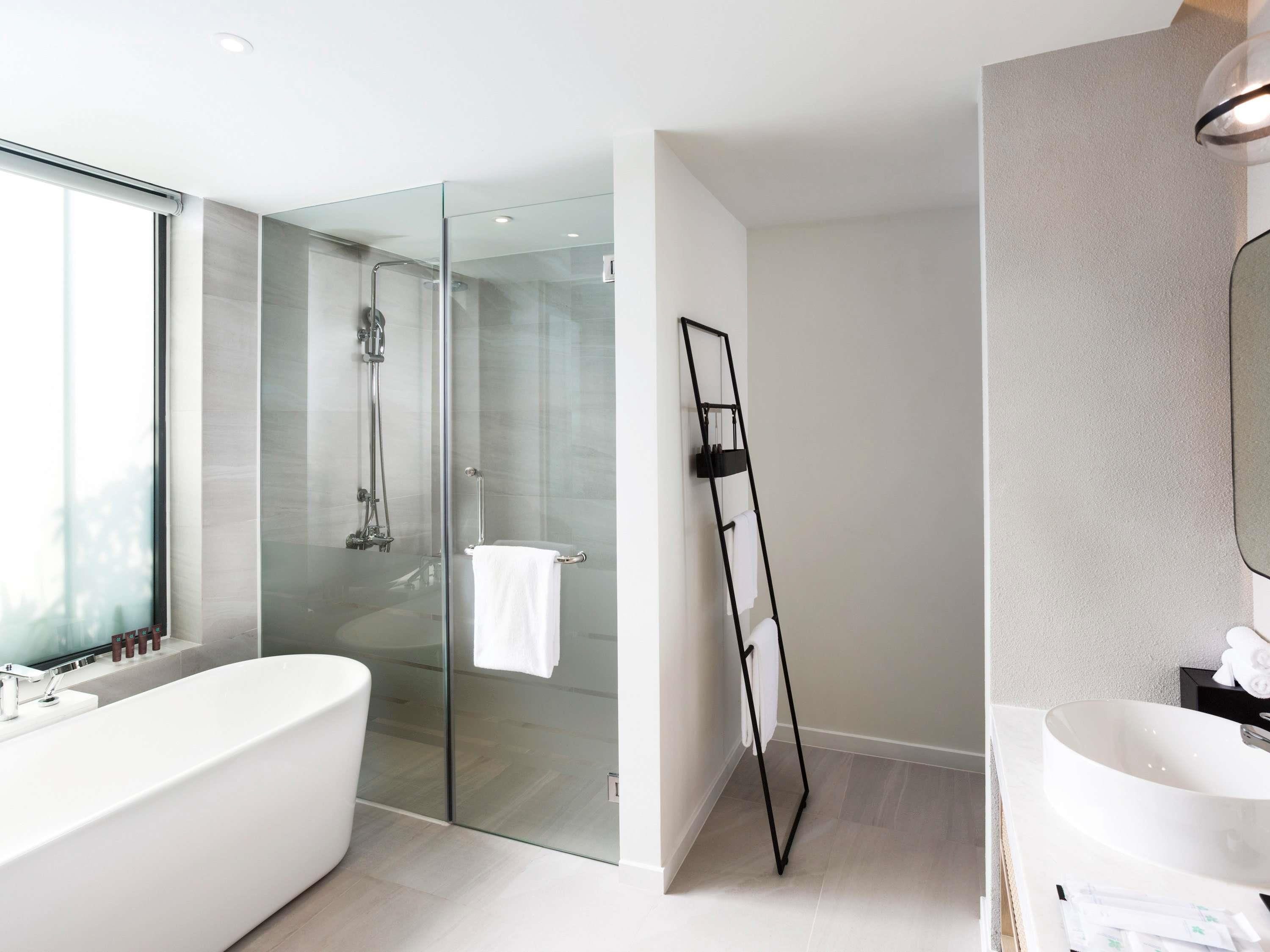 Un baño moderno con una bañera independiente, una ducha con mampara de vidrio y un espejo grande.