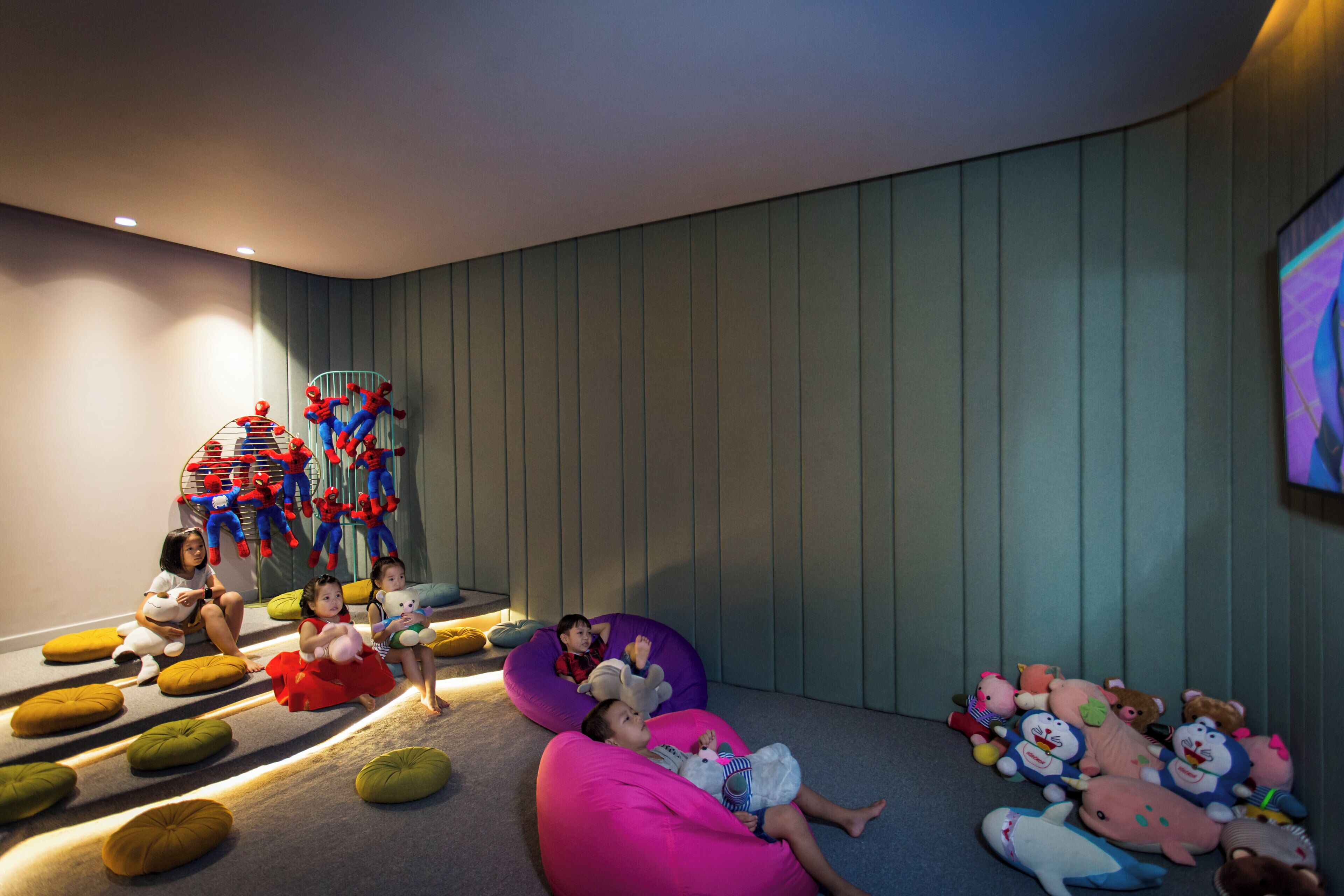 A room with a curved ceiling, a large screen on the wall, and children playing with toys.