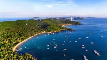 A coastal area with a beach, boats, and a lighthouse.