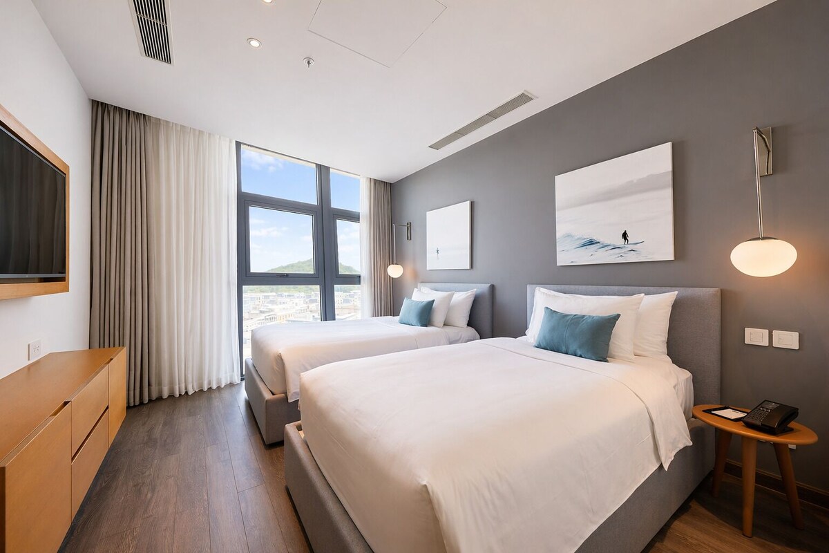 Habitación de hotel con dos camas, televisión, mesita de noche y ventana con cortinas.