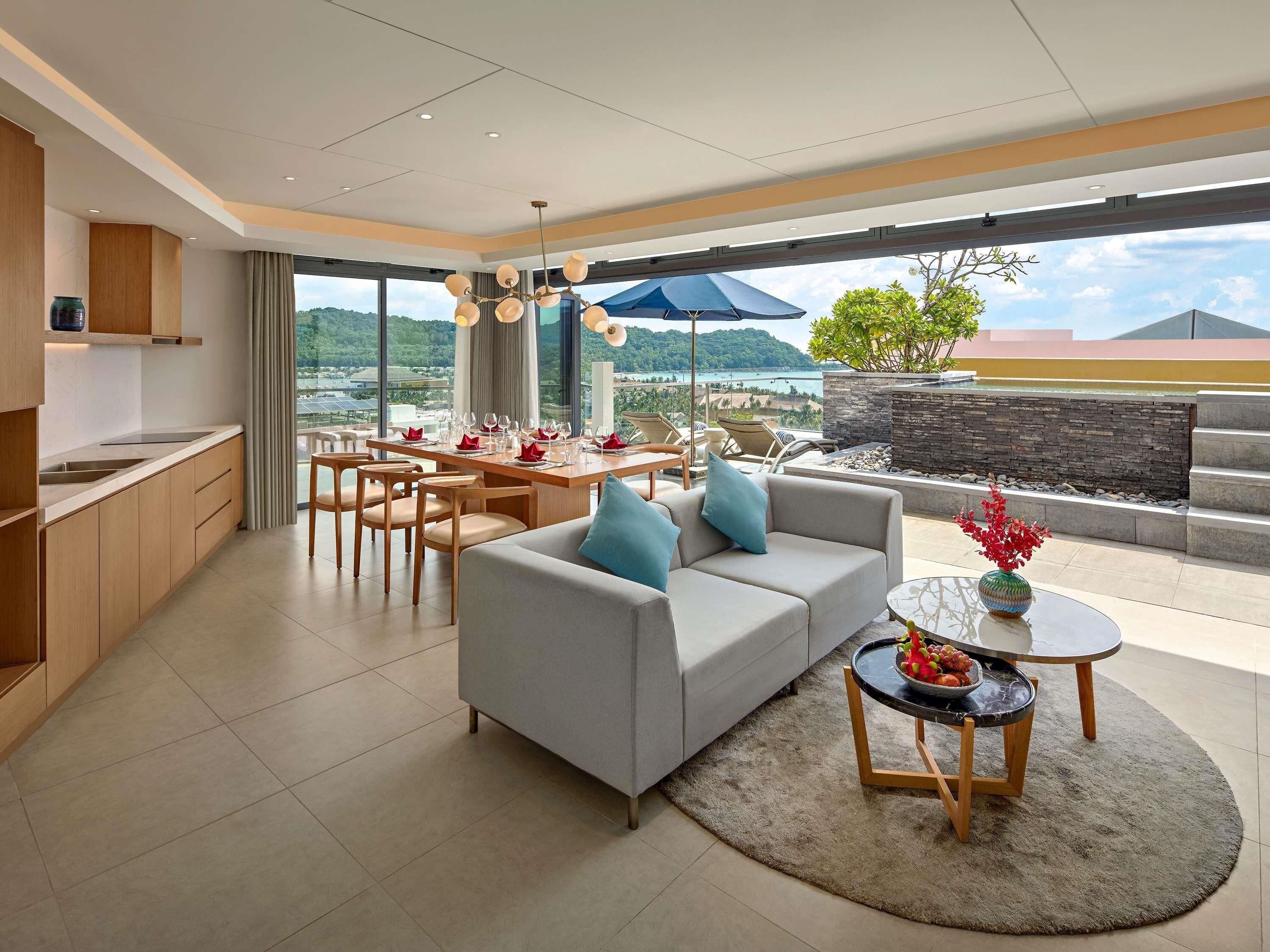 A modern living room with a sofa, dining table, and kitchen area.