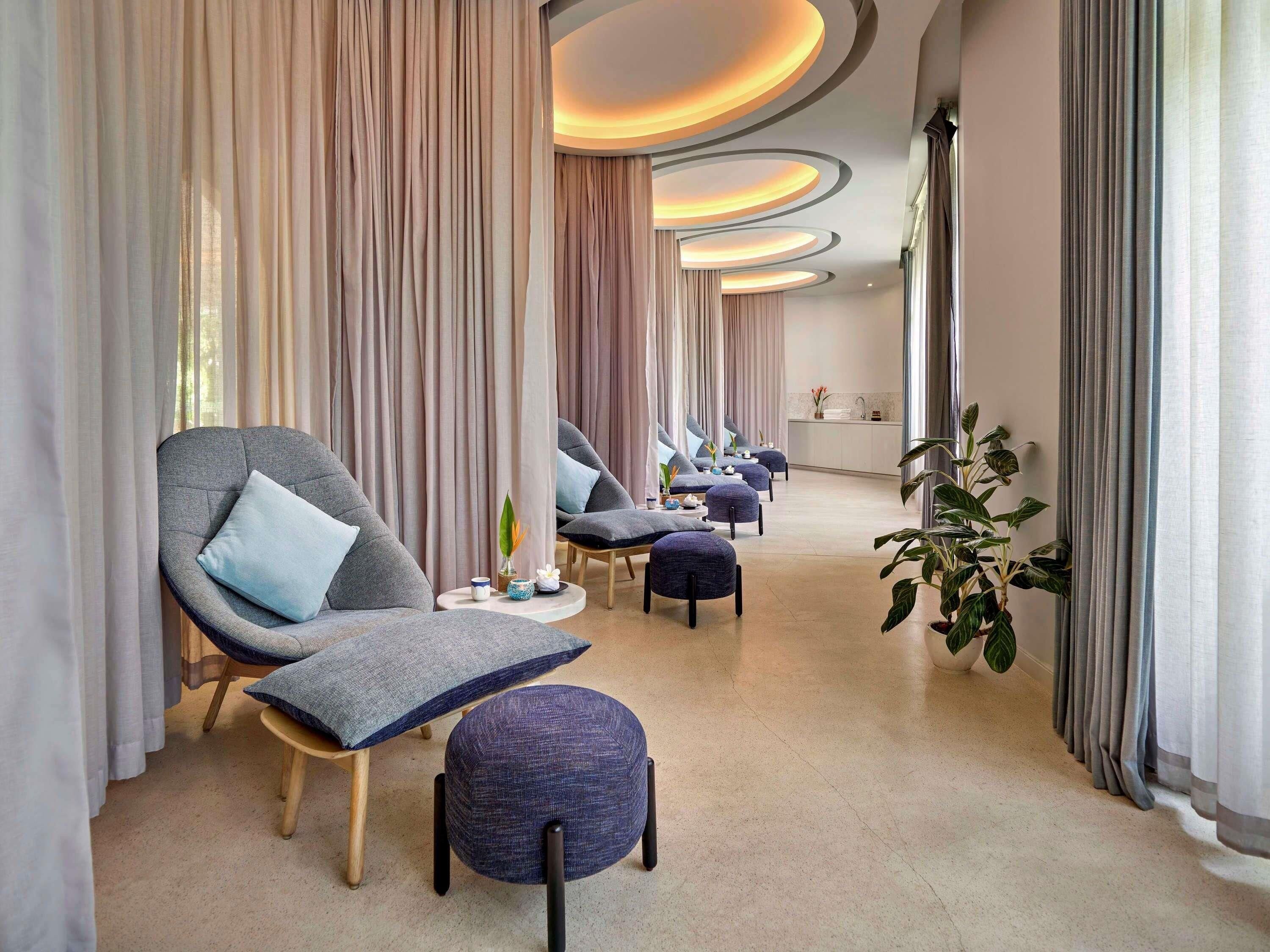 A modern interior with a seating area featuring sofas and ottomans, a small table with a vase, and a plant.