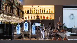 A bar area with neatly arranged liquor bottles and glasses, a large wine glass centerpiece, and a modern chandelier. - Hotel Kivir Adults Recommended, Historic City Center (Seville)