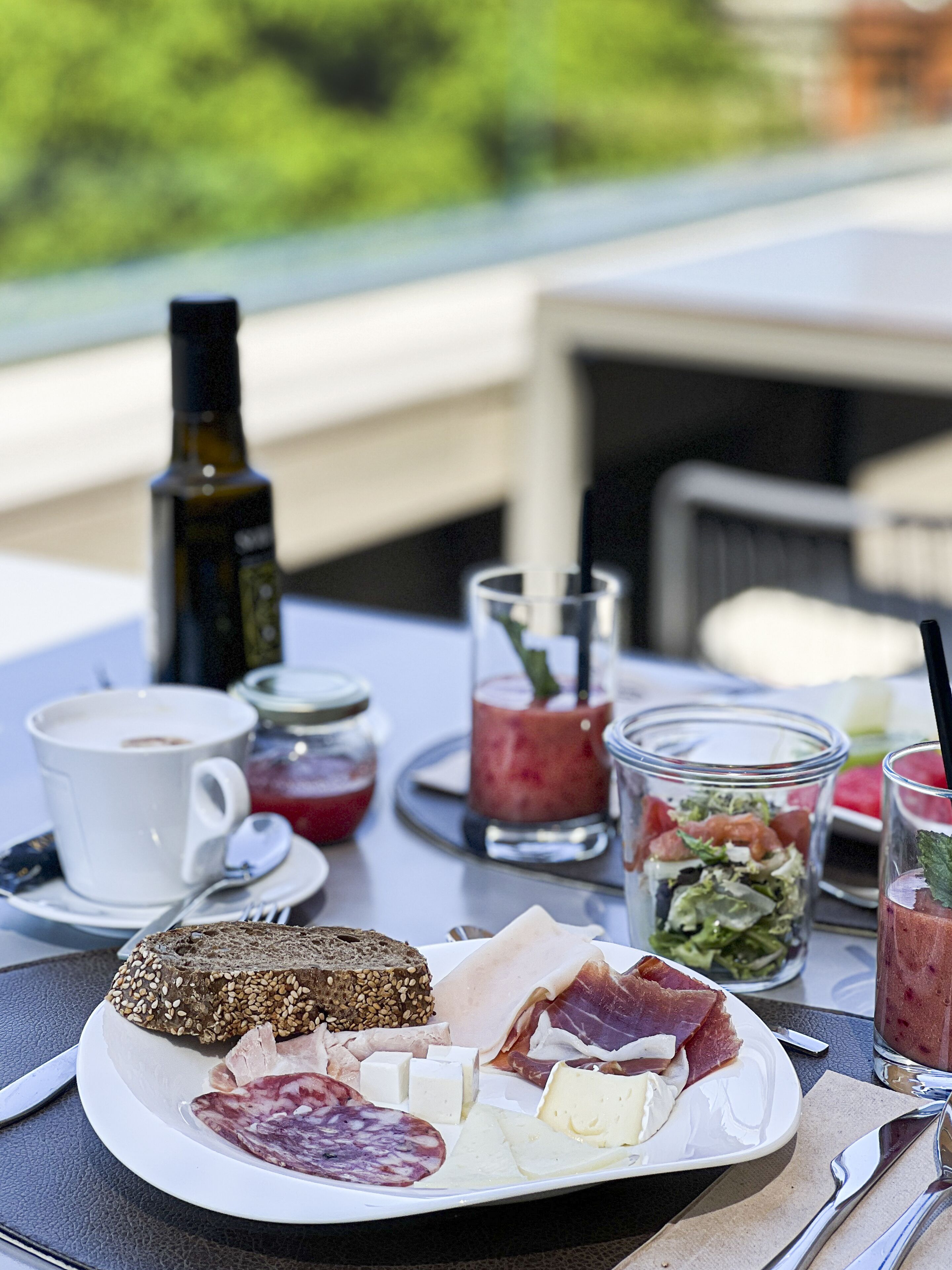 A breakfast table with a variety of foods including bread, cheese, meats, and drinks.
