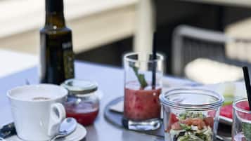 A breakfast table with a variety of foods including bread, cheese, meats, and drinks.