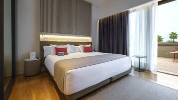 A modern hotel room with a large bed, a bedside table, a small round table, and a view of the outdoors.