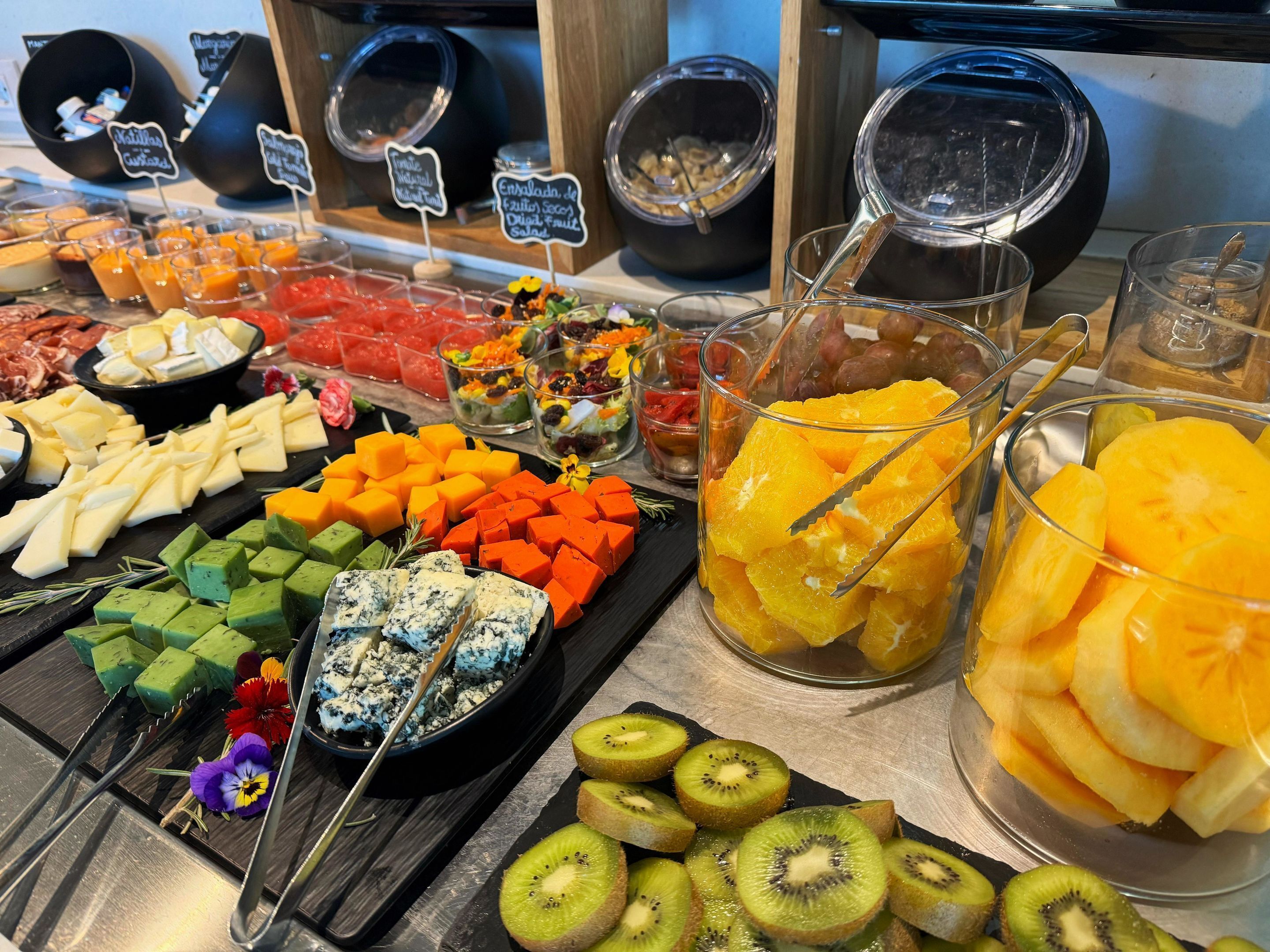 Un bufé con diversos alimentos, incluyendo queso, frutas y postres.