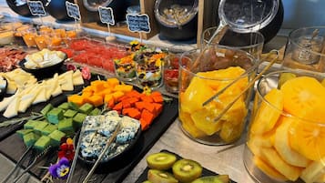 Un bufé con diversos alimentos, incluyendo queso, frutas y postres.