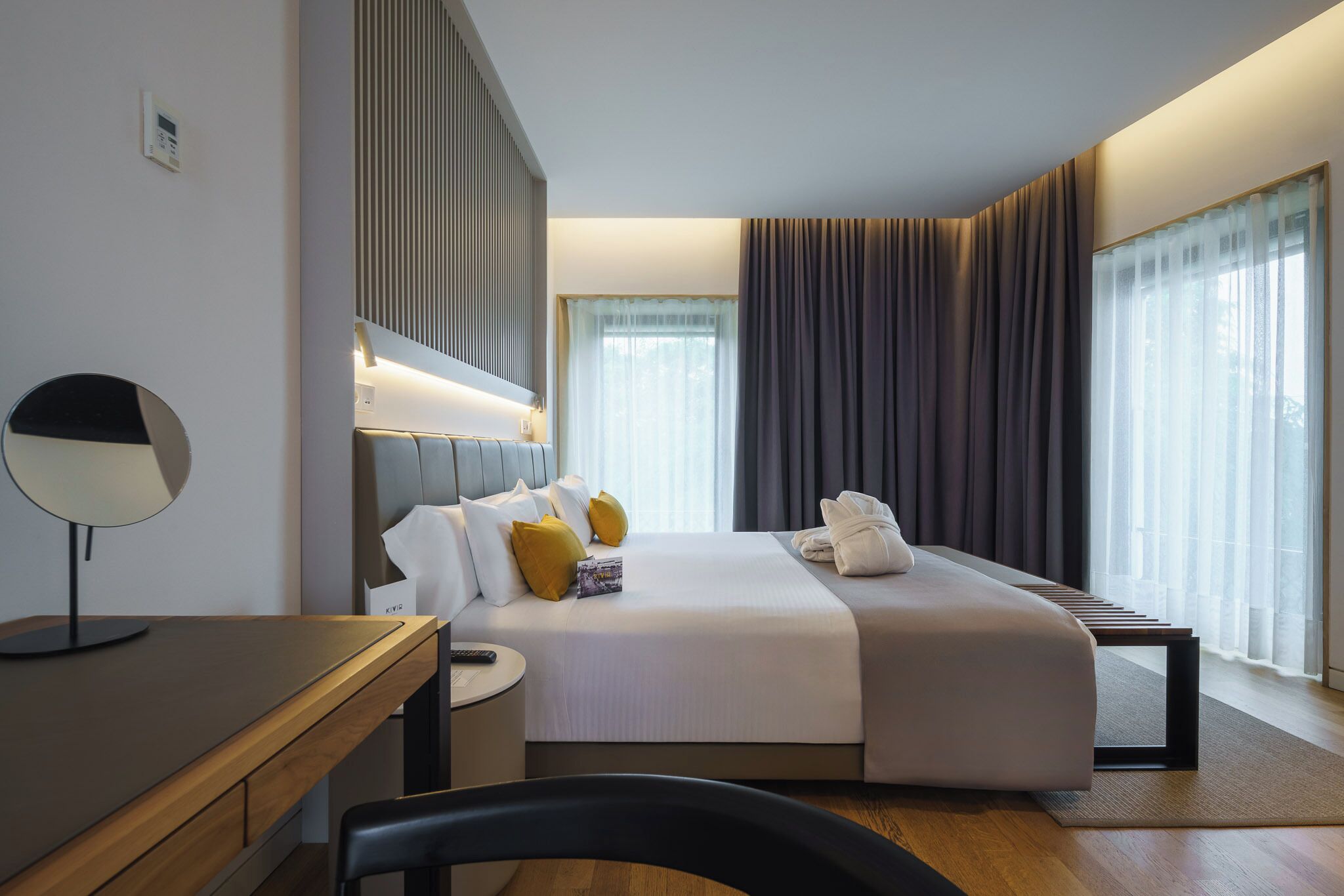 Ein modernes Hotelzimmer mit einem großen Bett, Nachttischen, einem Schreibtisch und einem Stuhl.