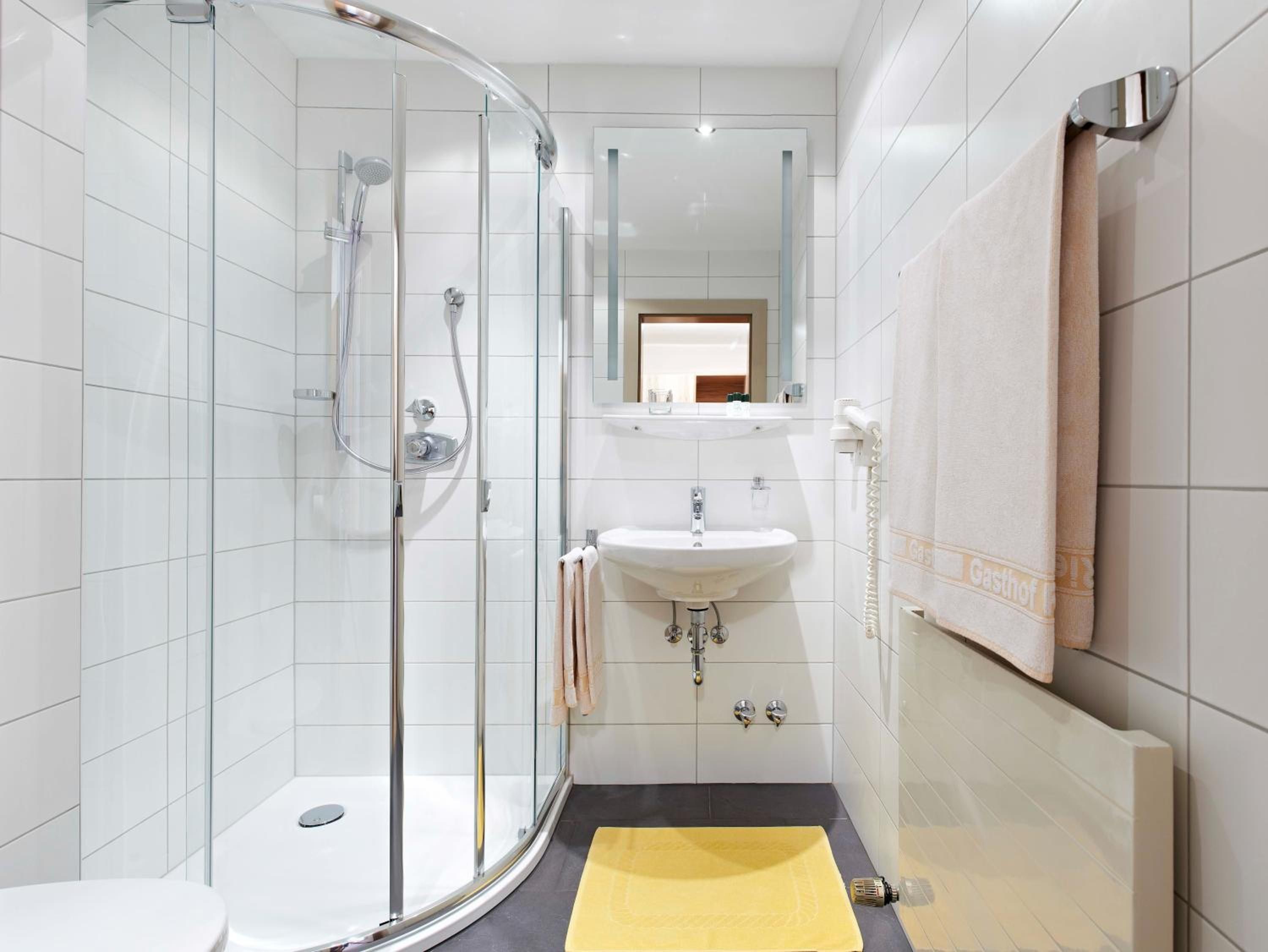 A modern bathroom with a glass-enclosed shower, a white sink, and a mirror above the sink.