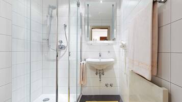 A modern bathroom with a glass-enclosed shower, a white sink, and a mirror above the sink.