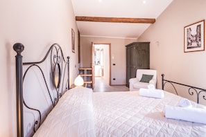 Une chambre avec un lit, une chaise, une armoire et un couloir menant à la cuisine.