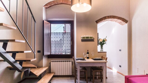 A modern kitchen with a dining table, wooden benches, and a window with a view.