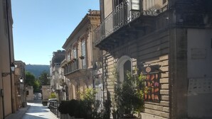 A narrow street lined with historic buildings, featuring balconies with wrought iron railings and potted plants. - Residenza Donnafugata B&B (Ragusa)