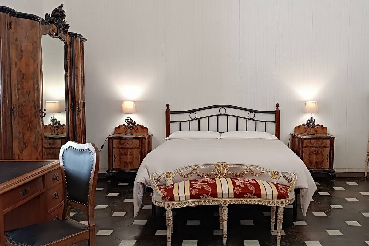 Ein Schlafzimmer mit einem Bett, einem Holzbüro, einem Stuhl und aufwendigen Möbeln.
