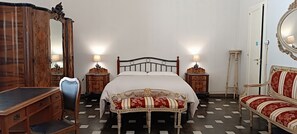 Une chambre à coucher avec un lit, un bureau en bois, une chaise et des meubles décoratifs.