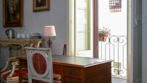 A room with a wooden desk, a chair, a lamp, and a window with a view of a balcony. - Residenza Donnafugata B&B (Ragusa)